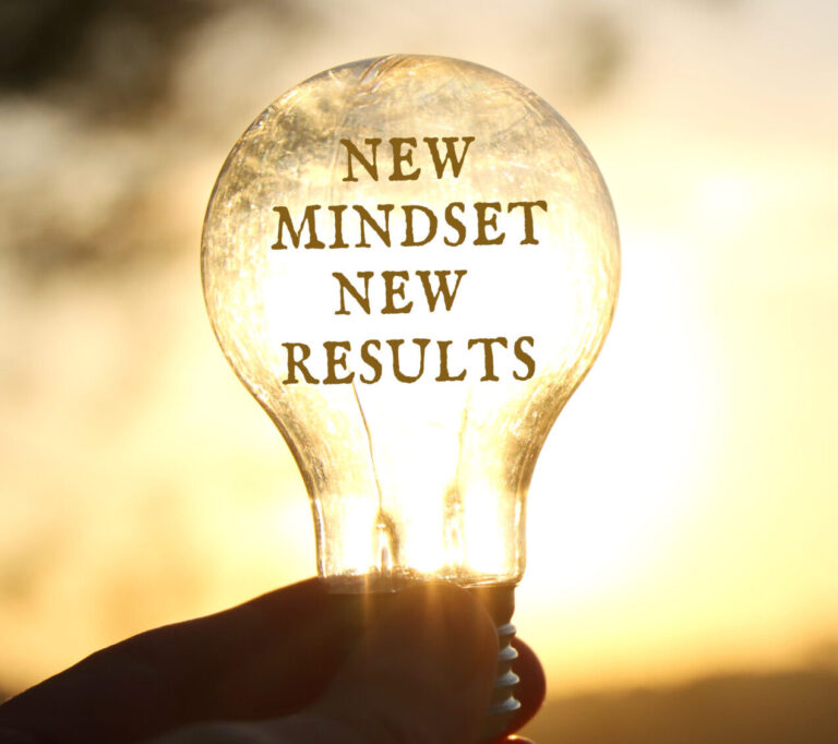 Hand holding a light bulb with the text new mindset in front of the bright sun -- signaling better ideas for a brighter tomorrow.