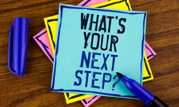 Hand written note to self on a sticky note stating "what is your next step?"